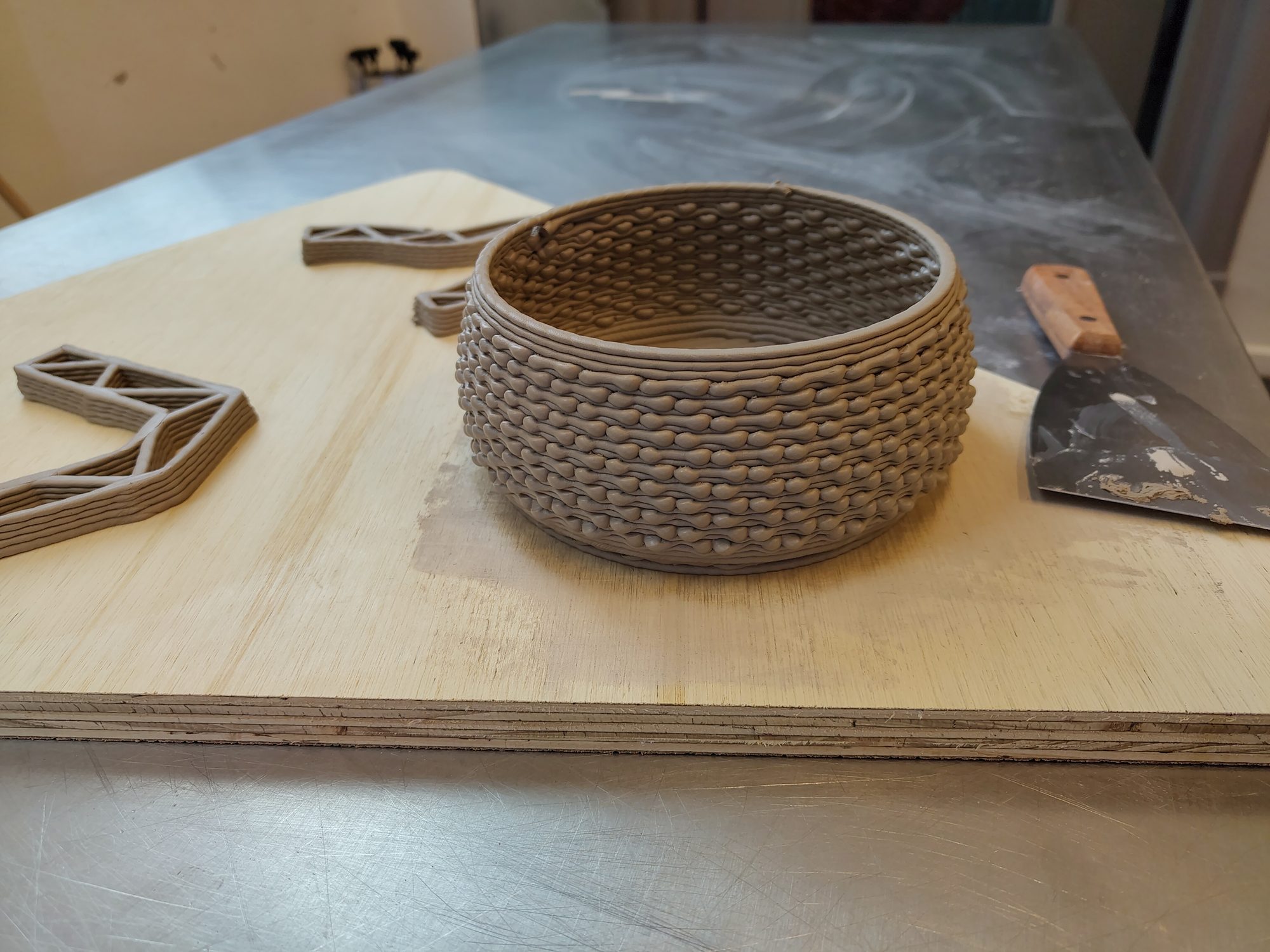 The studio bench with a printed vessel, hand tools and cut templates
